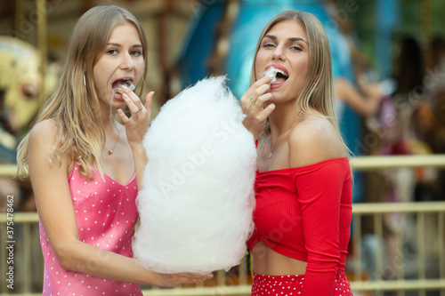 Happy young women having fun in the city and eating cotton candy.
