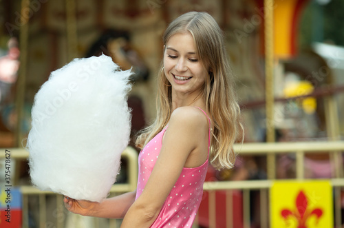 Smiling young girl eating cotton candy.