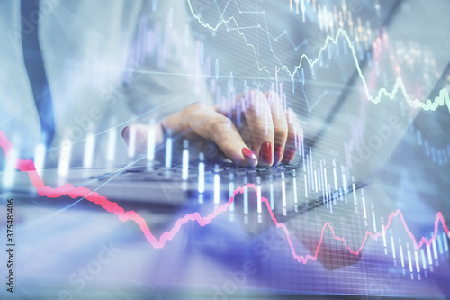 Double exposure of businesswoman hands typing on computer and financial graph hologram drawing. Stock market analysis concept.