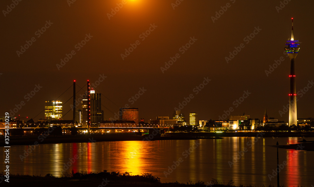 Naklejka premium Düsseldorf und Rheinturm unter dem Vollmond in orangem Farbton