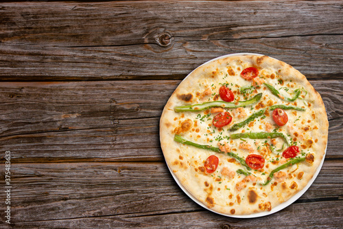 Vegetarian pizza with asparagus and cherry tomato top view on wooden background.