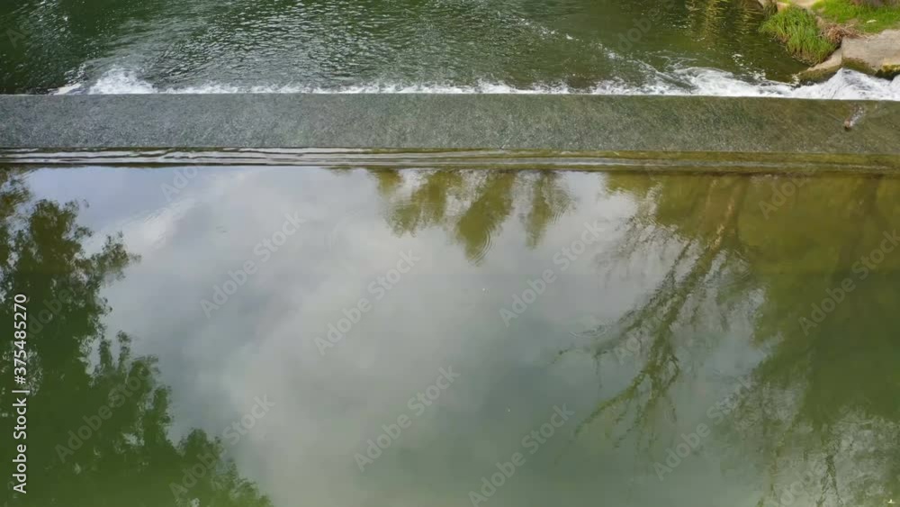 Low flight with a drone over a small but beautiful waterfall on a rural river on a cloudy day Low flight with a drone over a small but beautiful waterfall on a rural river on a cloudy day