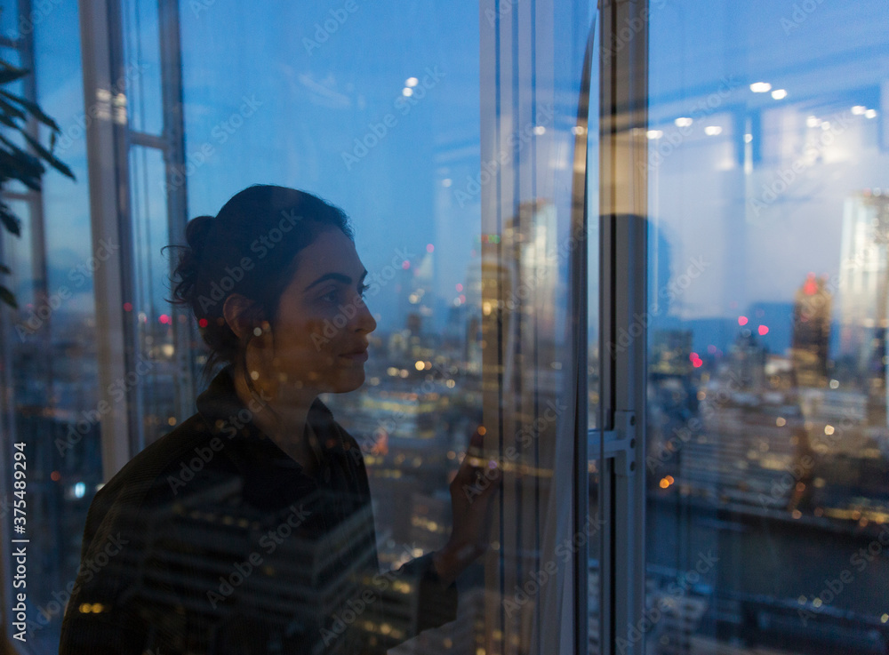 Thoughtful business woman working late at highrise office window Thoughtful business woman working late at highrise office window
