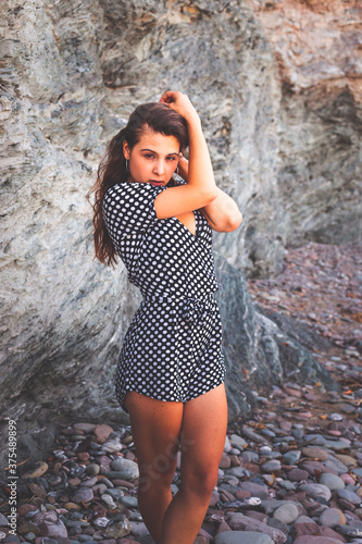Sensual girl in a rocky cove wearing a black and white dots dress