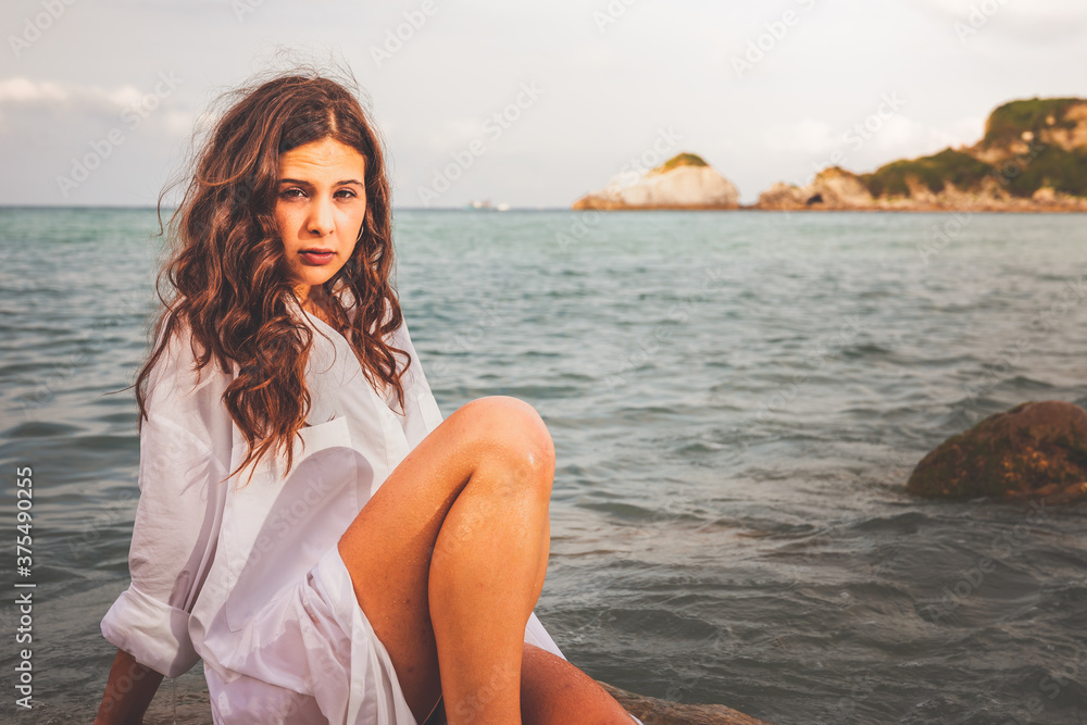 Sensual girl in a rocky cove with a big white shirt and a bikini. Sensual girl in a rocky cove with a big white shirt and a bikini.