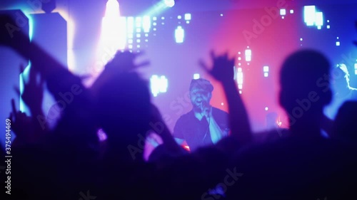 Wallpaper Mural Rock Band with Guitarists and Drummer Performing at a Concert in a Night Club. Front Row Crowd is Partying. Silhouettes of Fans Raise Hands in Front of Bright Colorful Strobing Lights on Stage.  Torontodigital.ca