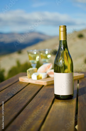 Blank label on white wine bottle with cheeseboard and view