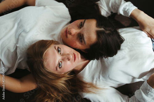 Two young women laying face to face on the floor