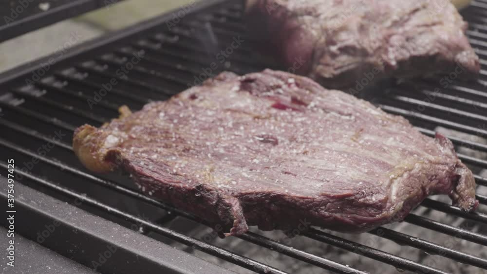 Close up on beef in the heat of the grill, ashes flying Close up on beef in the heat of the grill, ashes flying