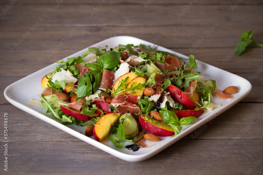 Peach and ham prosciutto salad on white plate. Horizontal photo
