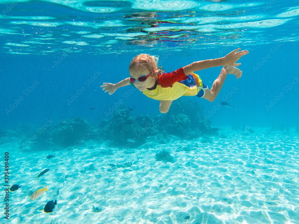 Child snorkeling. Kids swim underwater. Beach and sea summer vacation with children. Little boy watching coral reef fish. Marine life on exotic island. Kid swimming and diving with snorkel and mask.