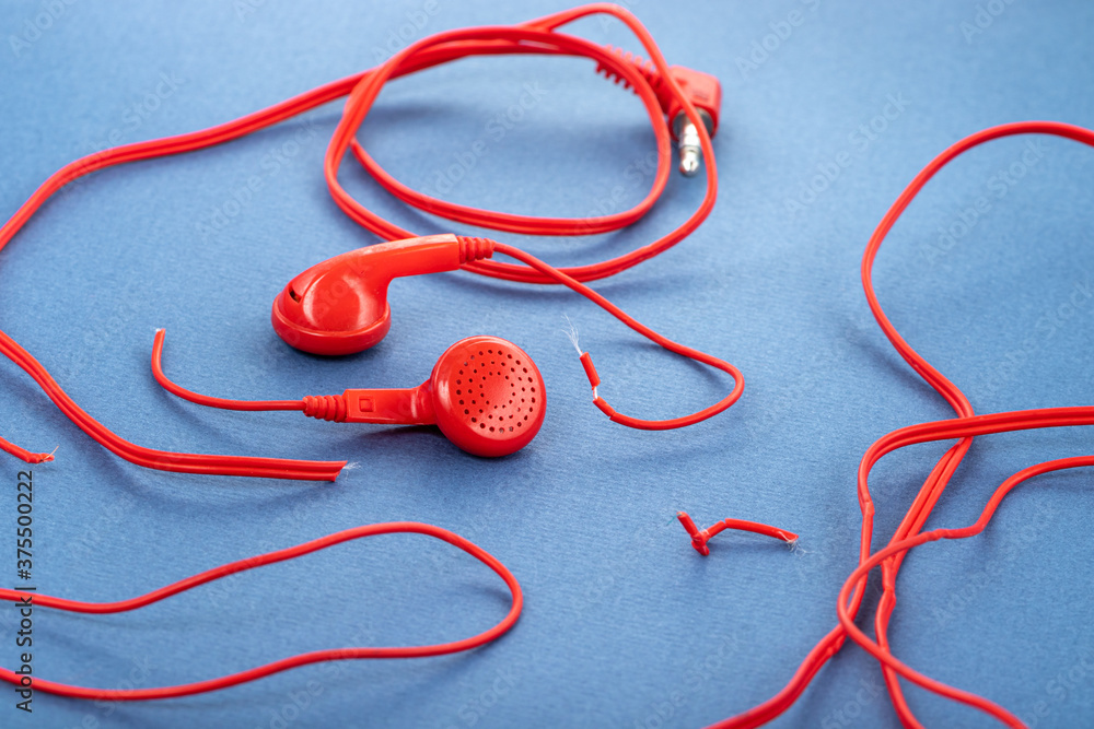 Headphones on a blue background. Torn headphones. Repair of electronic devices. Broken wire. Headphones on a blue background. Torn headphones. Repair of electronic devices. Broken wire.