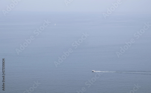 Foggy seascape with a motorboat visible in the foreground and a sailboat visible in the background