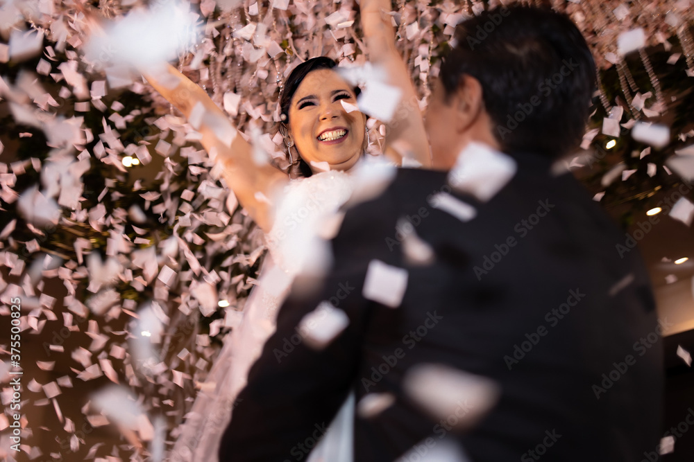 Latino Bride and Groom dancing and celebrating with white confetti flying around them Latino Bride and Groom dancing and celebrating with white confetti flying around them