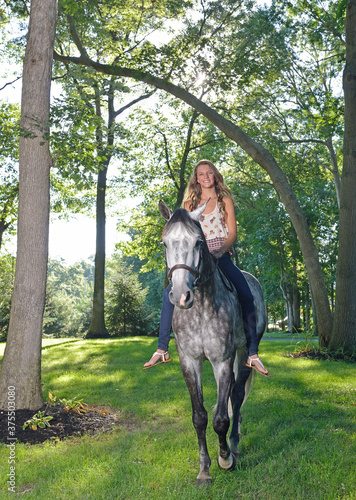Adorable young girl rides her horse on a farm