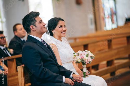 Latino bride and groom focused on what the priest is saying