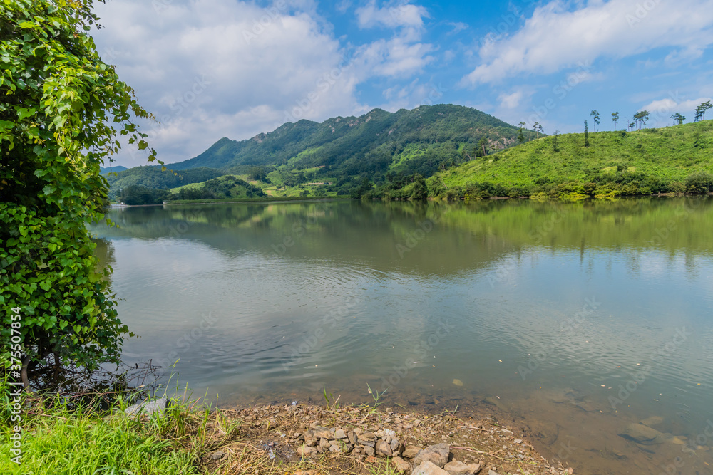 Rural landscape of lake with mountains and cloudy sky in background. Rural landscape of lake with mountains and cloudy sky in background.