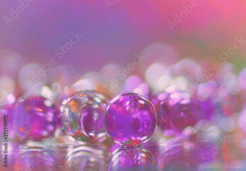 Abstract  of pink and translucid bubbles with reflections on a mirror and a multicolor bokeh background fine art photography