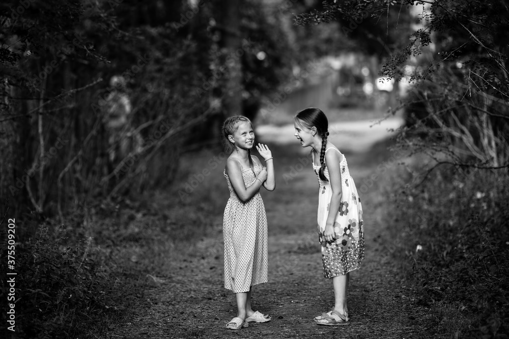 Fototapeta premium Two ten-year-old girls friends in pine Park.. Black and white photography.