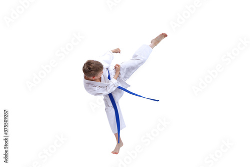 On white isolated background little sportsman with blue belt training kick