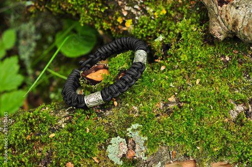 Braided paracord bracelet black among green grass left side