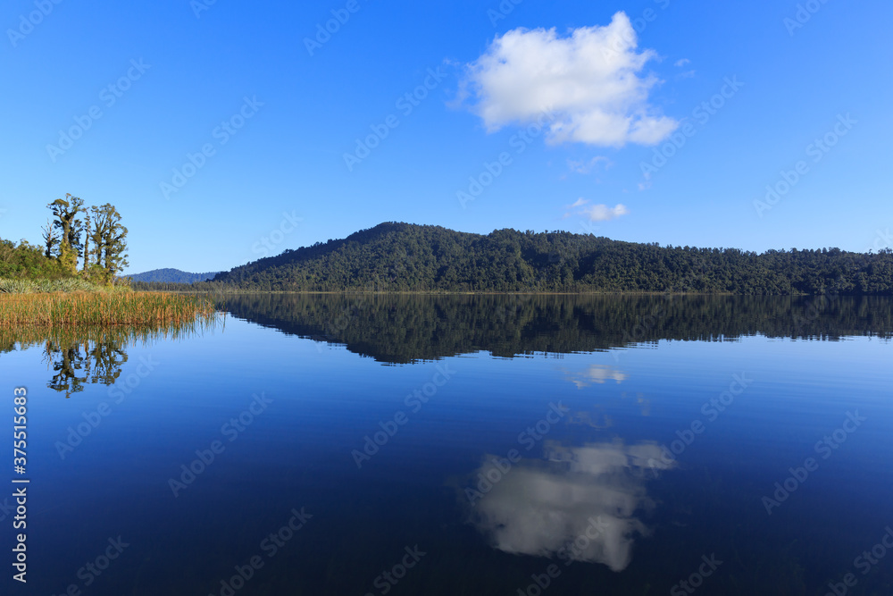 Calm mirror lake in the morning with mountain background in New Zealand.
