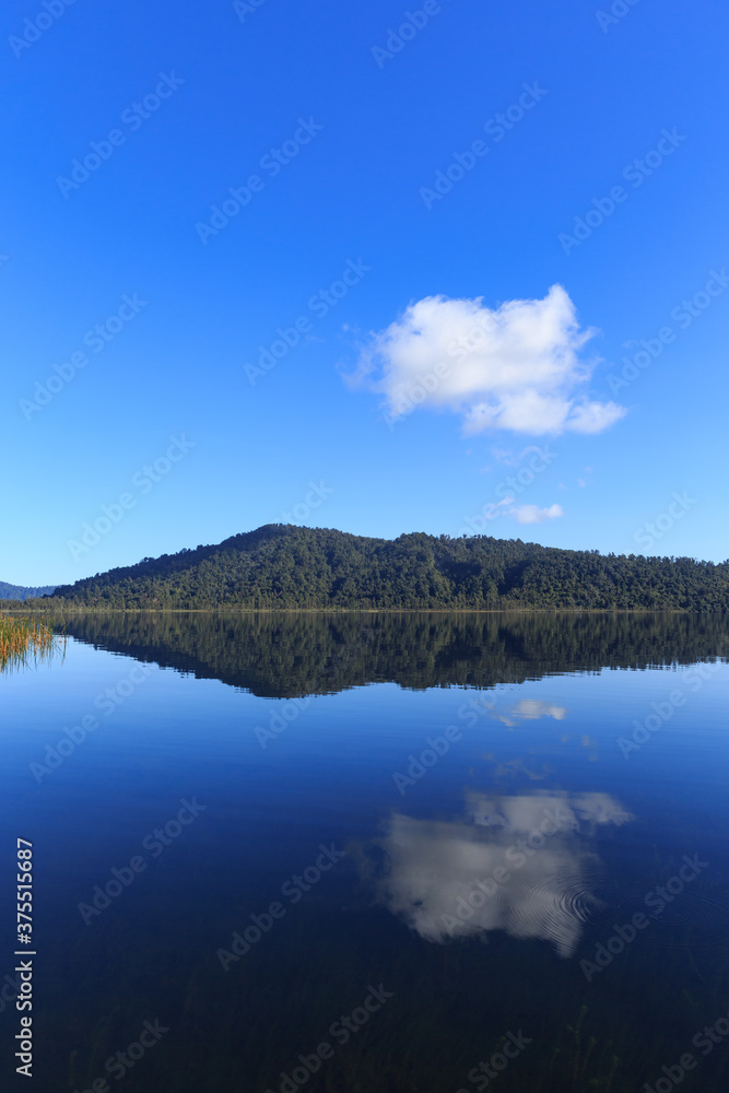 Calm mirror lake in the morning with mountain background in New Zealand.