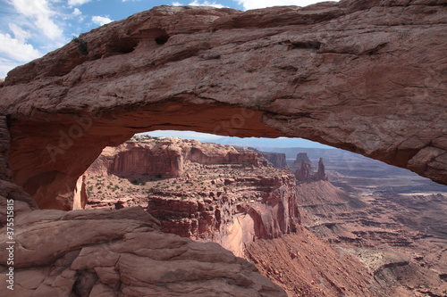View of Mesa Arch at island in the sky and landscape of Canyonlands National Park appearing under the arch in Utah, USA
