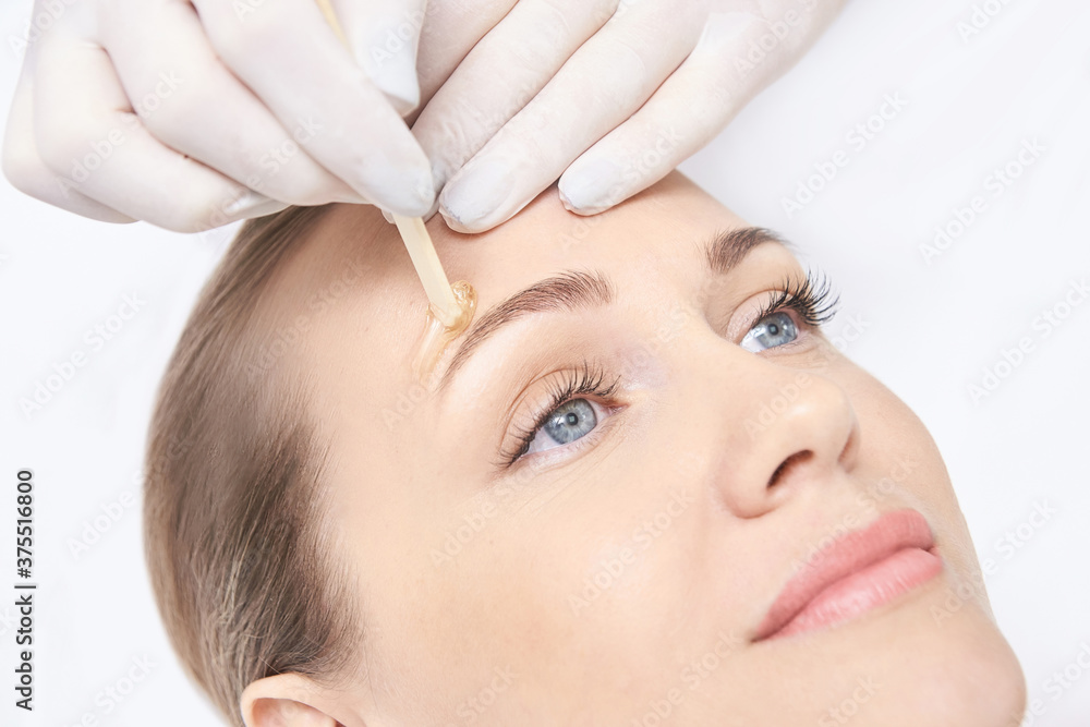 Hot hair removal depilation. Female skin routine. Sugar bodycare. Wax Eyebrow correction. Professional cosmetologist help girl. Sugaring bodycare cosmetics.