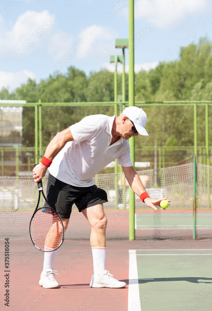An elderly man plays tennis on an outdoor court An elderly man plays tennis on an outdoor court