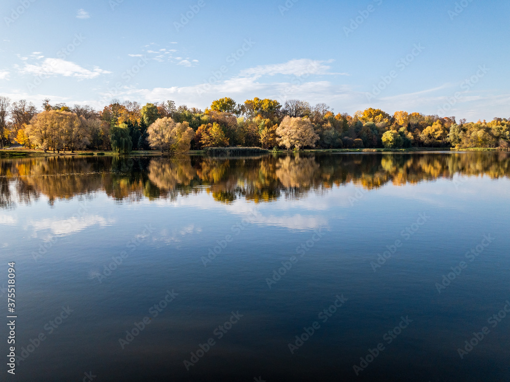 beautiful park view in autumn. calm lake with reflections of colorful trees and blue sky