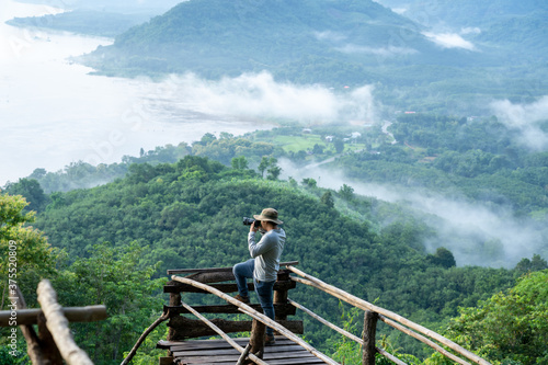 Photographer traveler standing takes a photo in the between mountains and the Mekong river at Phu Huai E -San fog aerial view landscape Sang Khom, Nong Khai Thailand. photo