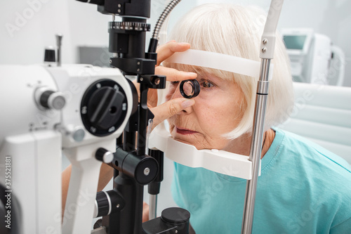 Senior woman eyesight test with binocular slit-lamp. Checking retina of a female eye close-up. Ophthalmology clinic photo