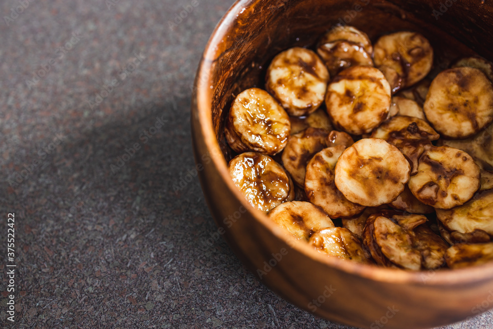 simple food ingredients, sliced banana in wooden bowl with melted cocoa powder coating simple food ingredients, sliced banana in wooden bowl with melted cocoa powder coating