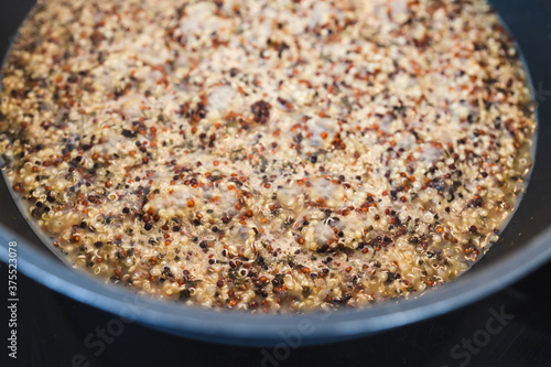 plant-based food, tricolor quinoa seasoned with nutritionalyeast getting boiled in pot on the stove
