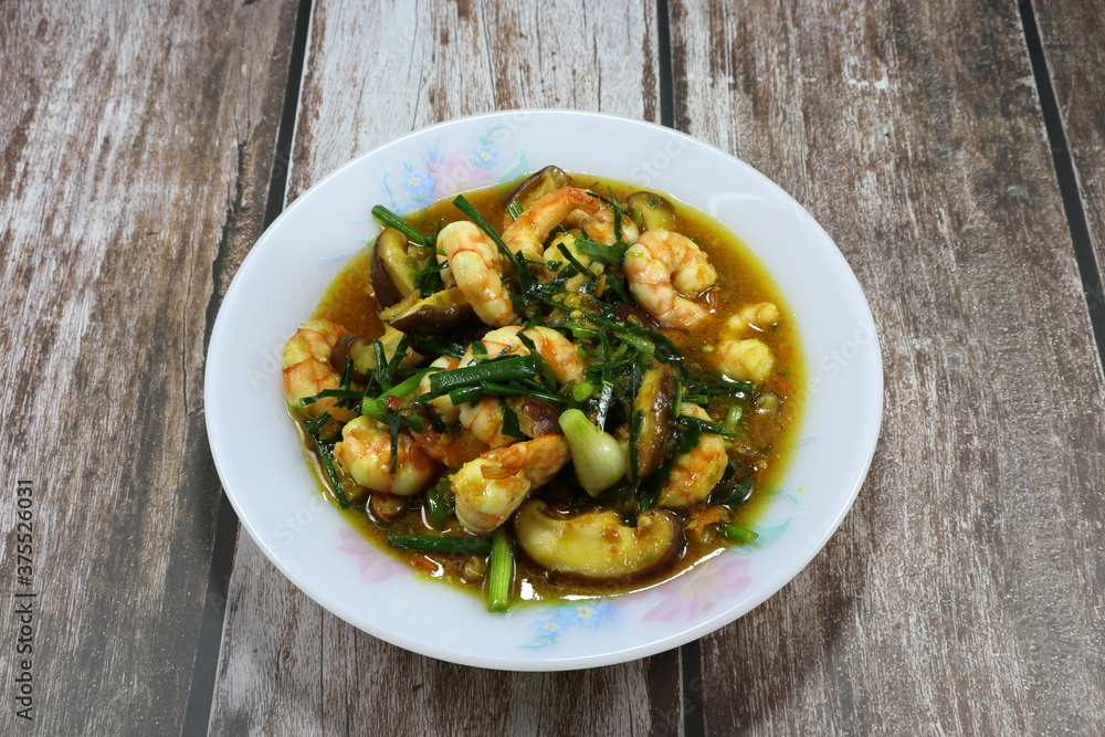 Traditional fried and stirred fresh peeled shrimp with cutting mushroom, basil and turmeric powder on the plate. Famous hot and spicy seafood menu in Asia restaurant. Traditional fried and stirred fresh peeled shrimp with cutting mushroom, basil and turmeric powder on the plate. Famous hot and spicy seafood menu in Asia restaurant.