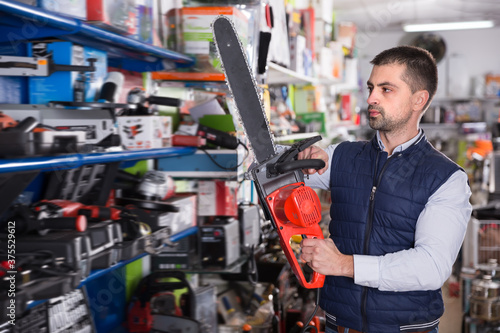 Man is buying new electric saw in tools store