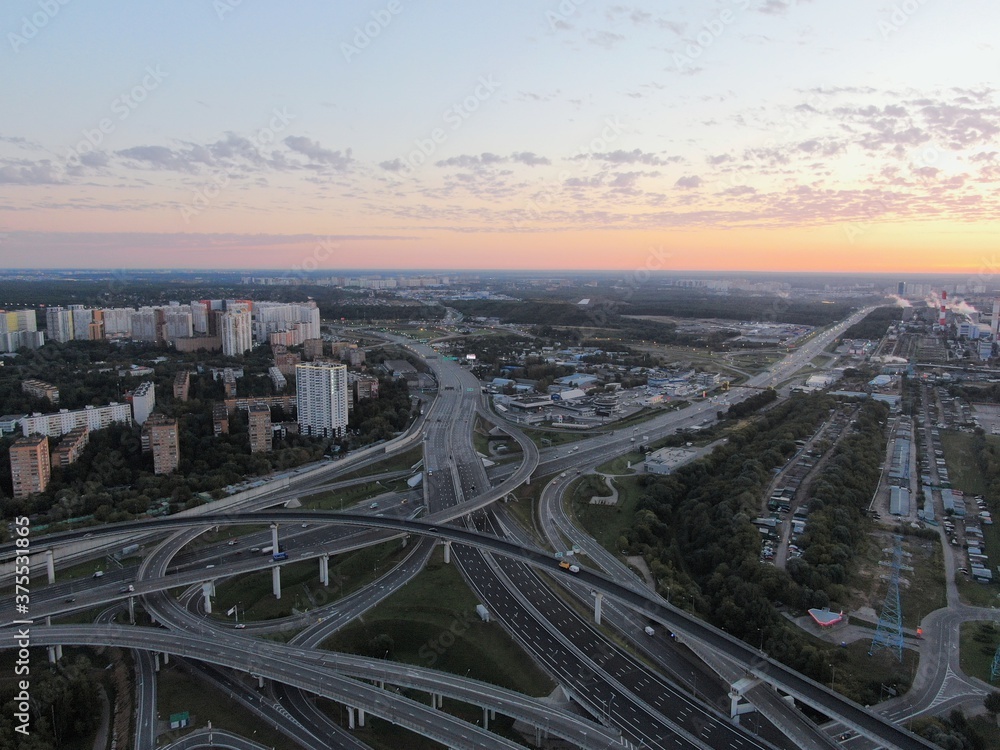 Aerial view panoramic landscape of Moscow city at sunrise. Multi-level intersection on an expressway in the city in the rays of the golden sun. Drone shot