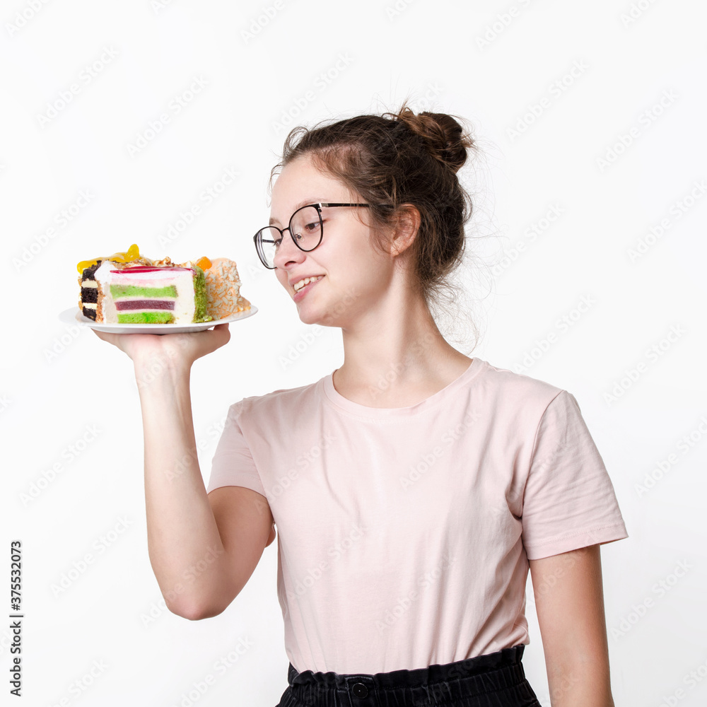 Happy beautiful cute teen girl in glasses and t-shirt with smile on face holding plate of cakes on white background Happy beautiful cute teen girl in glasses and t-shirt with smile on face holding plate of cakes on white background