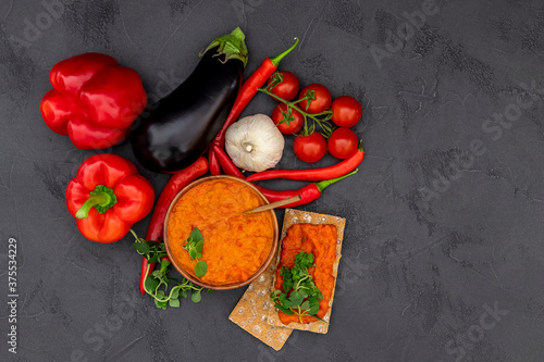 Traditional autumn Balkan vegan spread Ajvar, malidzano, or pinjur made of red bell pepper, chili, eggplant, tomatoes, and garlic. Homemade relish. Top view, copy space. photo