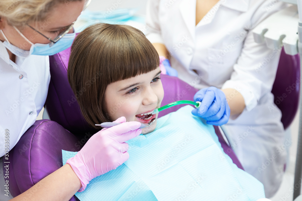 Dentist with assistant treating little girl teeth. Dentist with assistant treating little girl teeth.