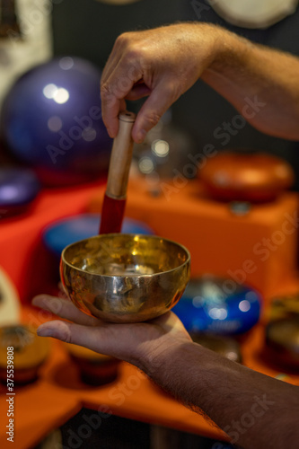 Man playing on tibetian singing bowl. Relaxation, meditative and traditional music concept. Close up shot. Soft focus background