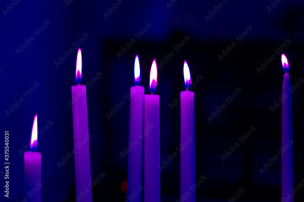 Colorful light candle flame close-up in church for religious ritual. Soft focus background. Colorful light candle flame close-up in church for religious ritual. Soft focus background.
