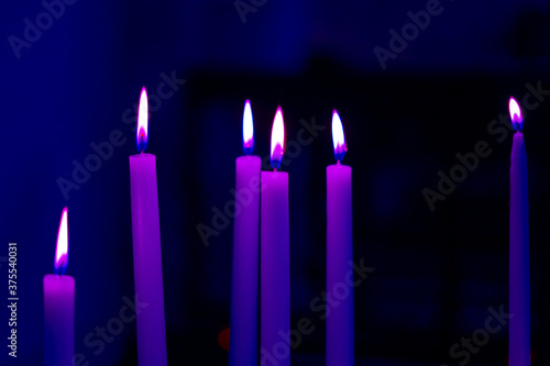 Colorful light candle flame close-up in church for religious ritual. Soft focus background.