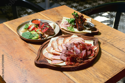 Georgian cuisine foodset from grilled steak with vegetables and different kinds of meat on rusitc wooden table. photo