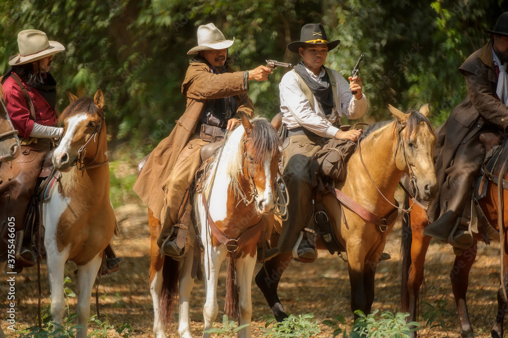 Three cowboys on horseback stand in the forest and carry guns.
Three cowboys on horseback stand in the forest and carry guns.