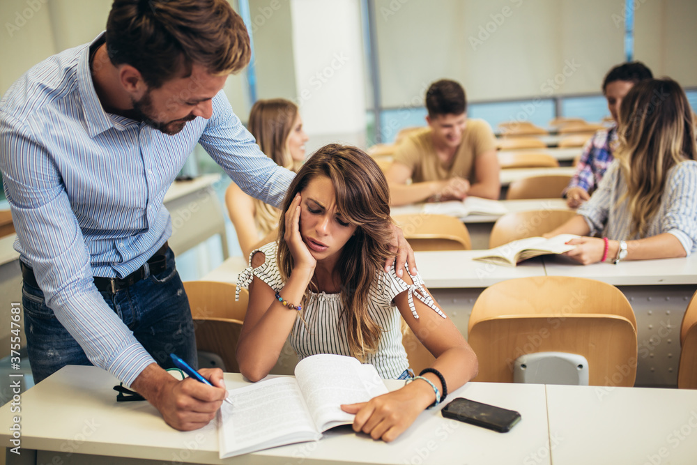 Fototapeta premium Professor helping a student in classroom at college