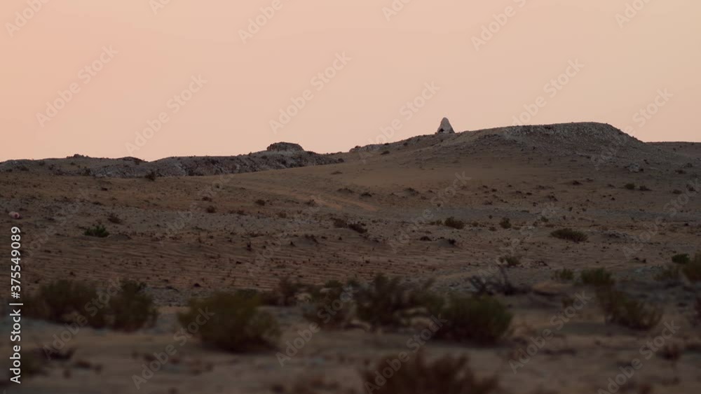 Wide camera tracking from left to right showing a man made landmark on top of the hill in Qatari desert. Wide camera tracking from left to right showing a man made landmark on top of the hill in Qatari desert.