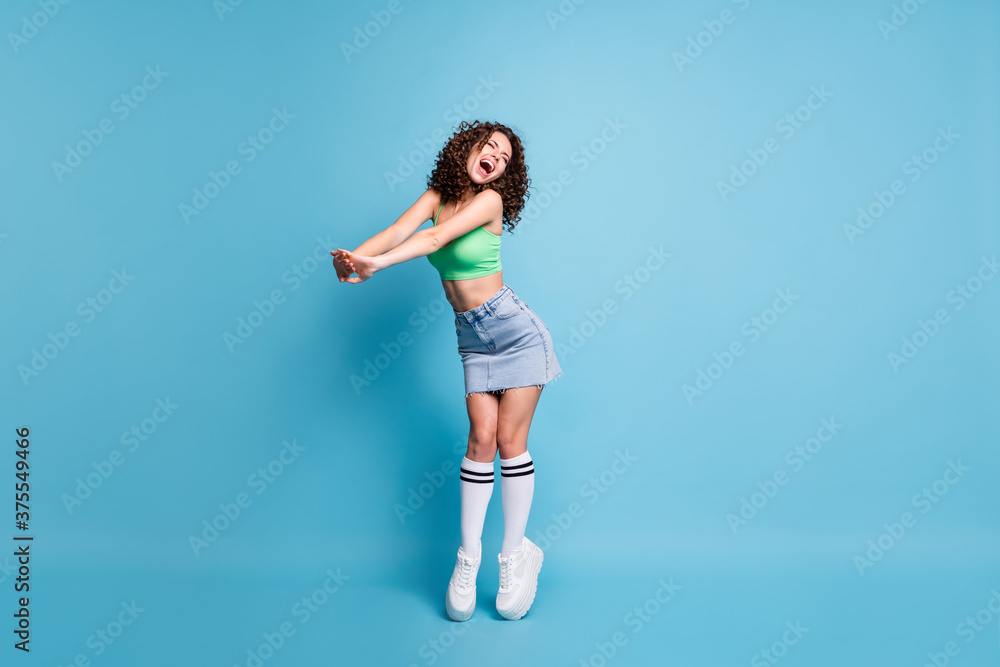 Full size photo of careless yelling lady model hands forward tiptoes perform stage concert summer camp entertainment advert wear green top denim skirt isolated pastel blue color background