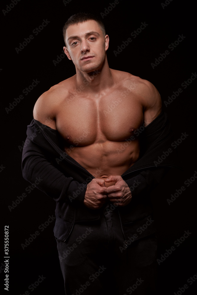Fototapeta premium Bodybuilder standing in black hoodie. Studio shot. Isolated